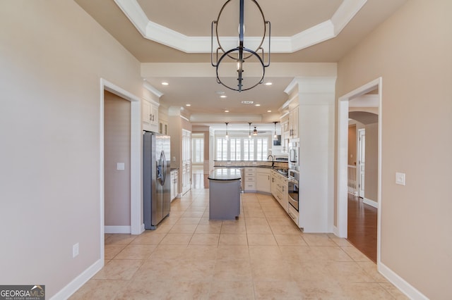 6706 Amherst Dr, Hoschton, GA 30548 - kitchen with stainless steel appliances, ornamental molding, white cabinets, a raised ceiling, and a chandelier