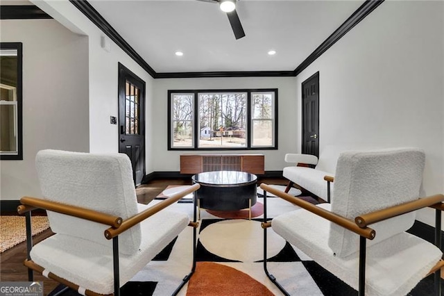 living area with wood-type flooring, ornamental molding, and ceiling fan