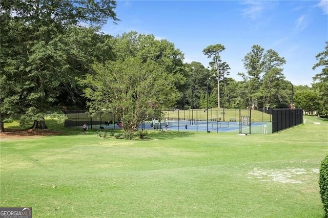 surrounding community with tennis court and a lawn