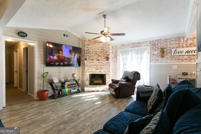 living room with wood walls, vaulted ceiling, a textured ceiling, a fireplace, and hardwood / wood-style floors