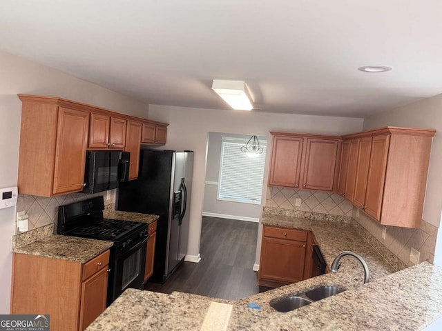 kitchen featuring light stone counters, sink, black appliances, and kitchen peninsula