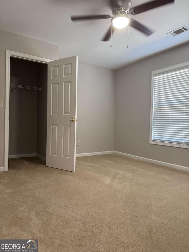 unfurnished bedroom with light colored carpet, ceiling fan, and a closet