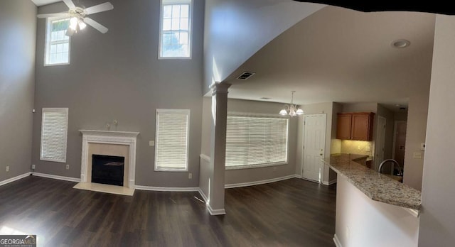 living room featuring ceiling fan with notable chandelier, dark hardwood / wood-style floors, a wealth of natural light, and a high end fireplace