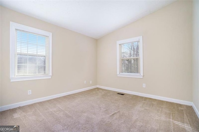 carpeted spare room with vaulted ceiling