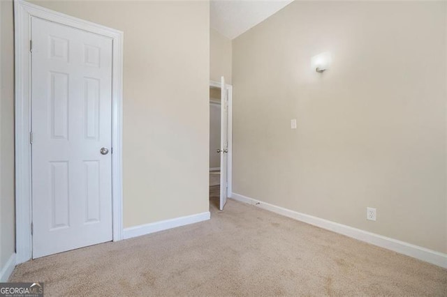 interior space featuring light colored carpet and lofted ceiling