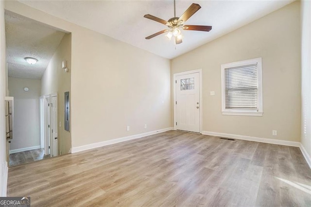 unfurnished room with ceiling fan, light hardwood / wood-style floors, vaulted ceiling, and a textured ceiling