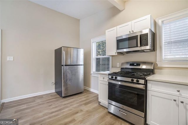 kitchen featuring white cabinetry, stainless steel appliances, lofted ceiling with beams, and light hardwood / wood-style flooring