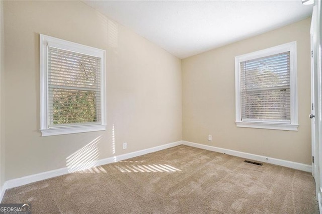 carpeted spare room with vaulted ceiling