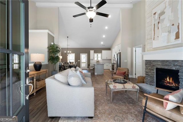 living room with high vaulted ceiling, a ceiling fan, dark wood-type flooring, and a stone fireplace