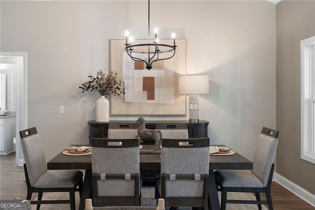 dining space with dark wood-style floors, a notable chandelier, and baseboards