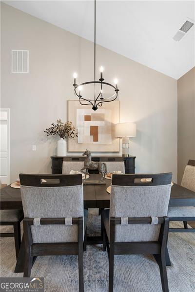 dining space featuring high vaulted ceiling, visible vents, a notable chandelier, and wood finished floors