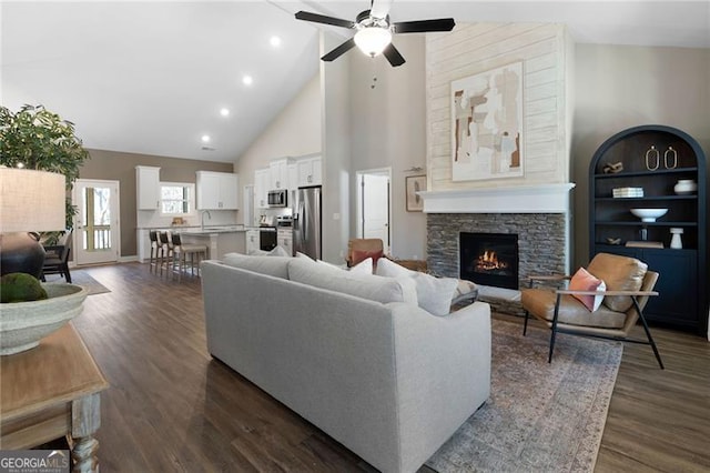 living room featuring a ceiling fan, dark wood-style floors, a fireplace, high vaulted ceiling, and recessed lighting