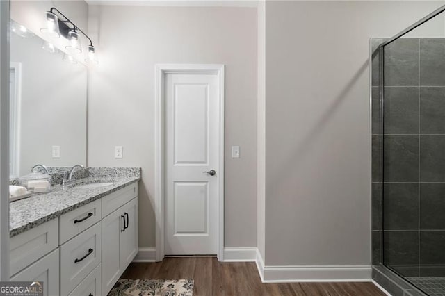 full bathroom with a stall shower, baseboards, wood finished floors, and vanity