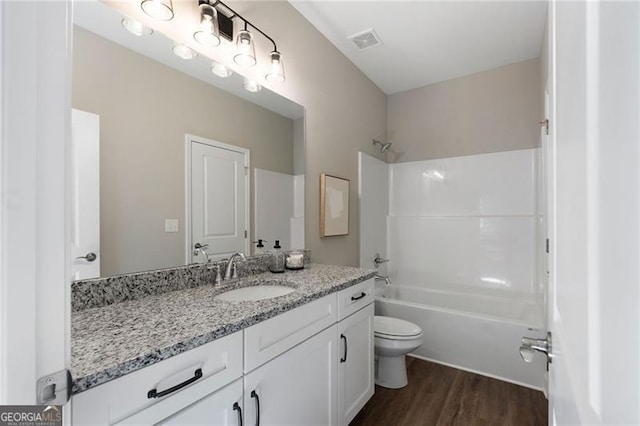 bathroom with toilet, wood finished floors, vanity, bathing tub / shower combination, and visible vents