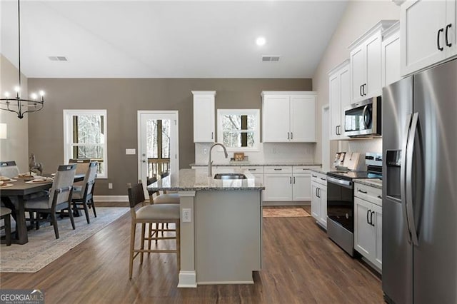 kitchen featuring visible vents, a kitchen island with sink, stainless steel appliances, white cabinetry, and a sink