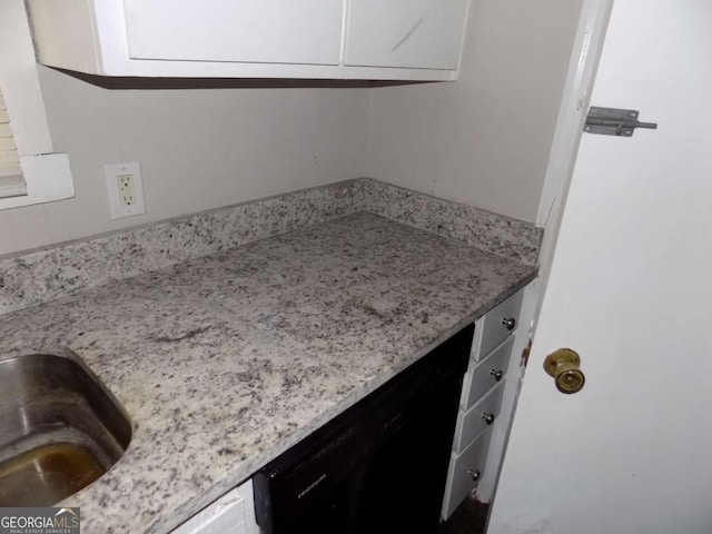 interior space with dishwasher, light stone countertops, and white cabinets