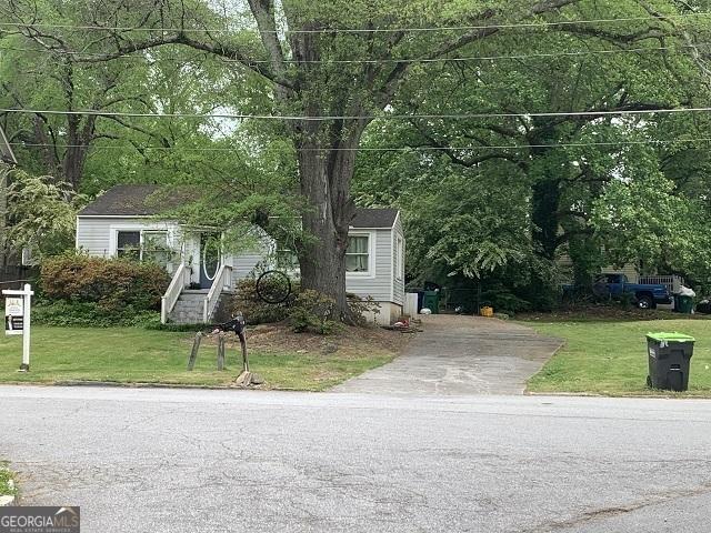 view of property hidden behind natural elements featuring a front lawn