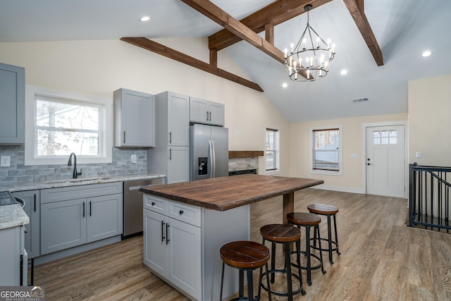 kitchen featuring a kitchen island, pendant lighting, butcher block countertops, sink, and stainless steel appliances