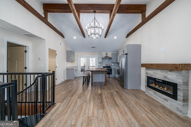 kitchen featuring wall chimney exhaust hood, stainless steel appliances, a tiled fireplace, and gray cabinetry