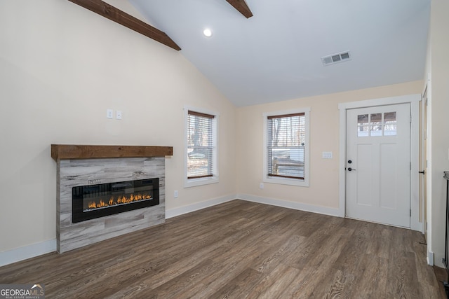 unfurnished living room featuring a tiled fireplace, high vaulted ceiling, dark hardwood / wood-style flooring, and beamed ceiling