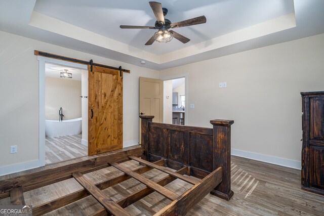 122 Acadia Dr Unit 110, Ellijay, GA 30540 - bedroom with a tray ceiling, a barn door, wood finished floors, baseboards, and ceiling fan