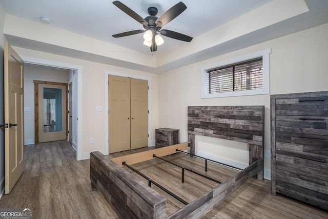 bedroom with hardwood / wood-style flooring, a raised ceiling, and a closet