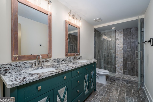 bathroom featuring vanity, a tile shower, and toilet