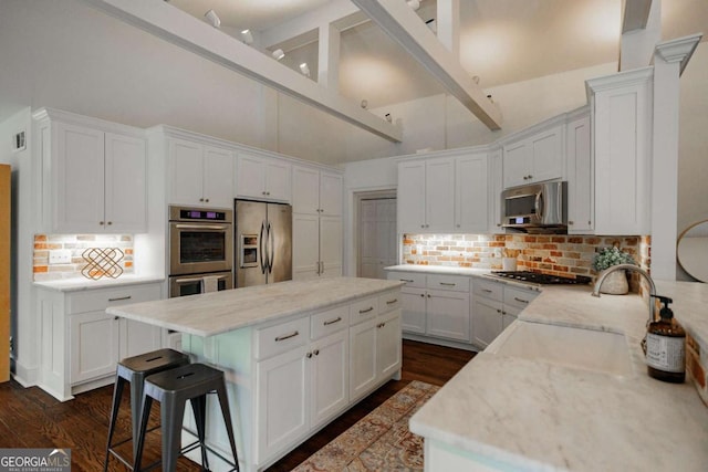 kitchen with sink, backsplash, white cabinets, light stone counters, and stainless steel appliances