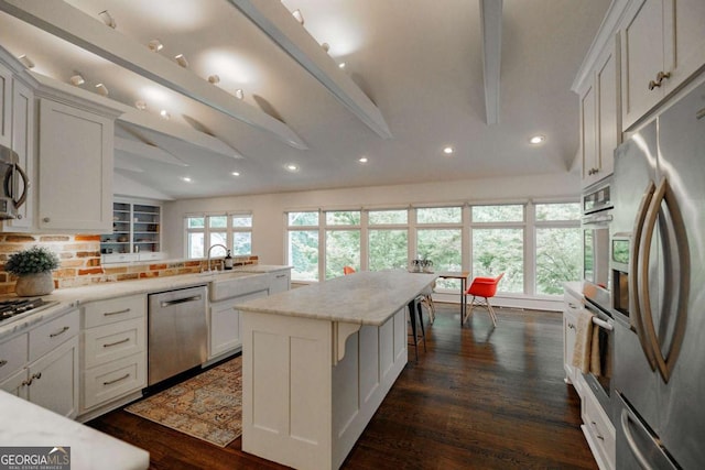 kitchen featuring lofted ceiling with beams, a kitchen breakfast bar, white cabinets, and appliances with stainless steel finishes