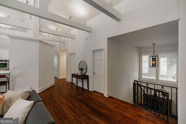 corridor with beam ceiling, dark hardwood / wood-style flooring, and high vaulted ceiling