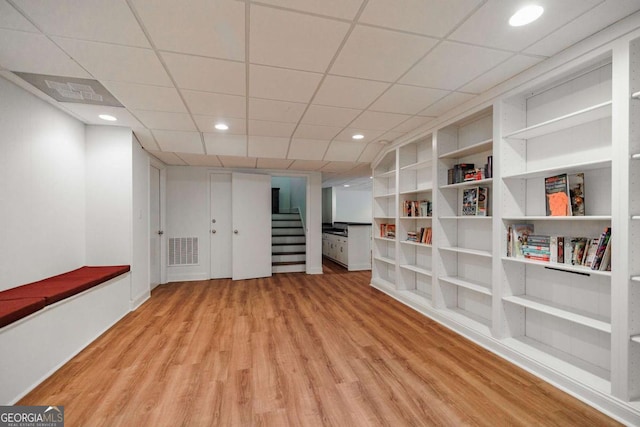 basement with built in features and light hardwood / wood-style floors