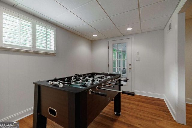 playroom with wood-type flooring and a paneled ceiling