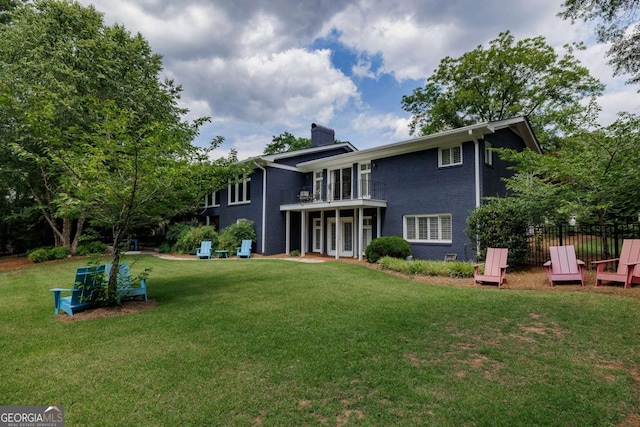 rear view of property with a yard and a balcony