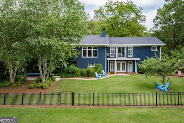 rear view of house with a lawn, french doors, and a balcony