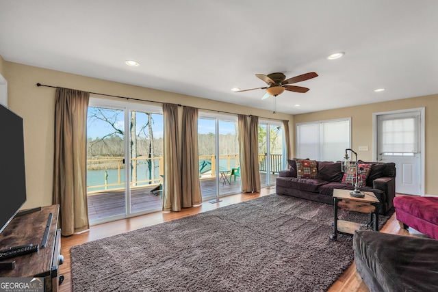 living room with a water view, ceiling fan, and light wood-type flooring