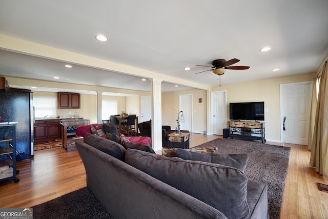 living room with ornate columns, ceiling fan, and light hardwood / wood-style flooring