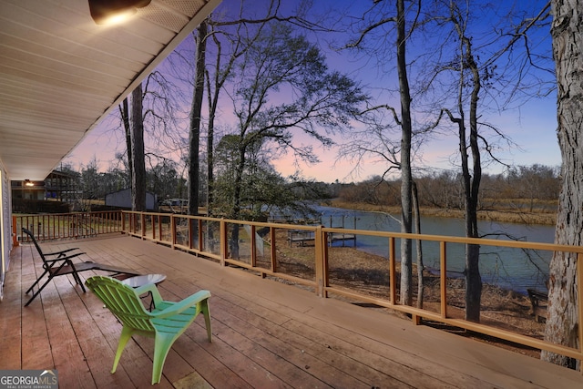 deck at dusk featuring a water view