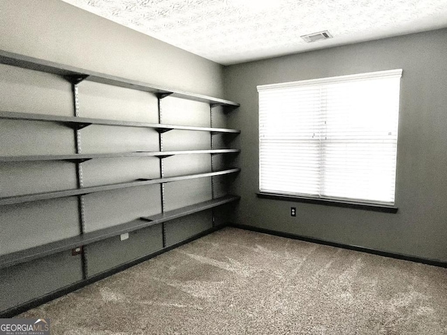 spare room with a textured ceiling and dark colored carpet