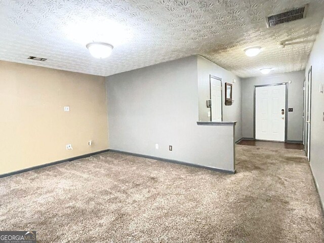 empty room with carpet and a textured ceiling