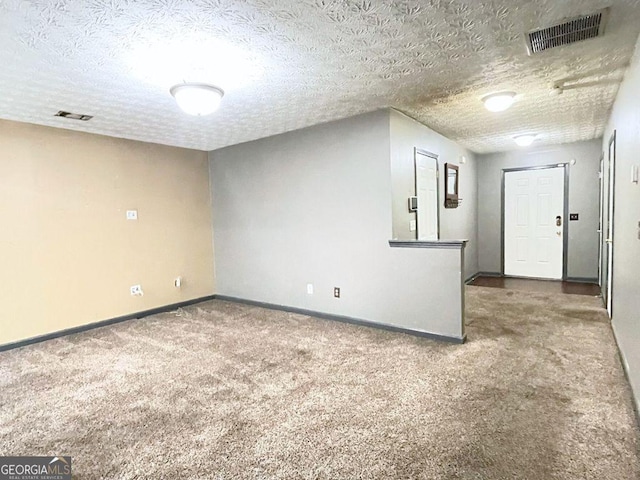 unfurnished room with carpet and a textured ceiling