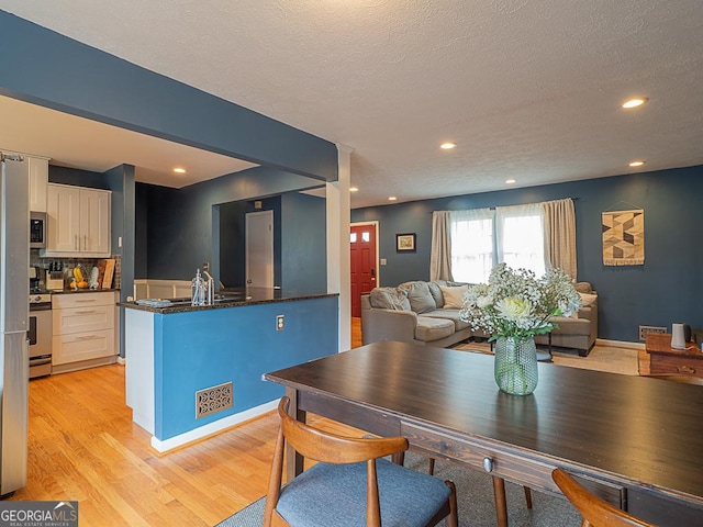 dining area with sink, a textured ceiling, and light hardwood / wood-style floors