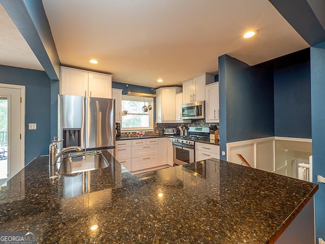 kitchen featuring white cabinetry, appliances with stainless steel finishes, sink, and dark stone countertops