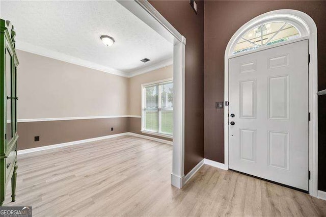 entryway with ornamental molding, a textured ceiling, and light hardwood / wood-style flooring