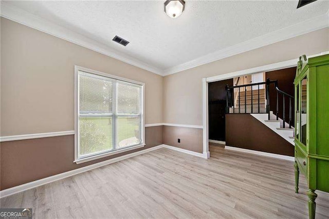 unfurnished room featuring ornamental molding, a textured ceiling, and light wood-type flooring