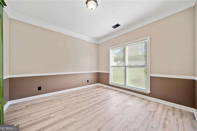 empty room featuring crown molding, light hardwood / wood-style flooring, and a textured ceiling