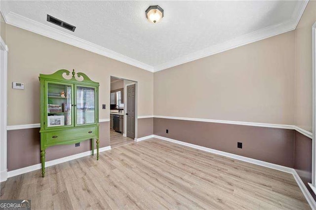 spare room featuring crown molding, a textured ceiling, and light wood-type flooring