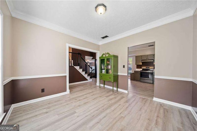 empty room featuring crown molding, light hardwood / wood-style floors, and a textured ceiling