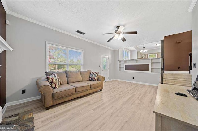 living room featuring built in shelves, ornamental molding, light hardwood / wood-style floors, and a textured ceiling