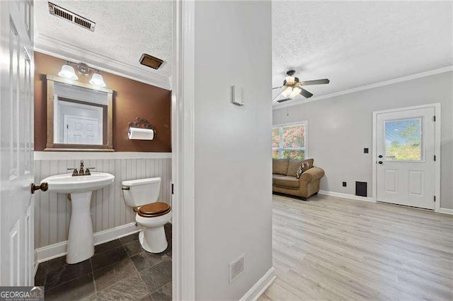 bathroom featuring ceiling fan, ornamental molding, toilet, and a textured ceiling