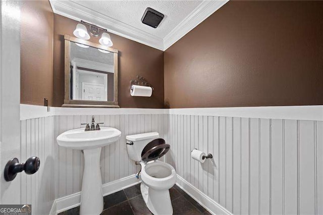 bathroom featuring toilet, sink, crown molding, a textured ceiling, and tile patterned flooring